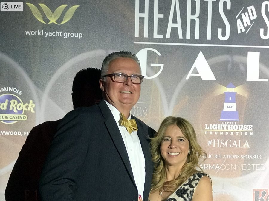 Guests posing at the Hearts and Stars Gala backdrop with sponsor logos